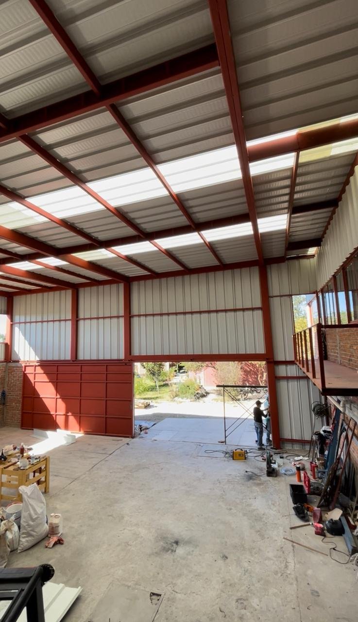 Nave industrial terminada con estructura metálica roja y portón corredizo